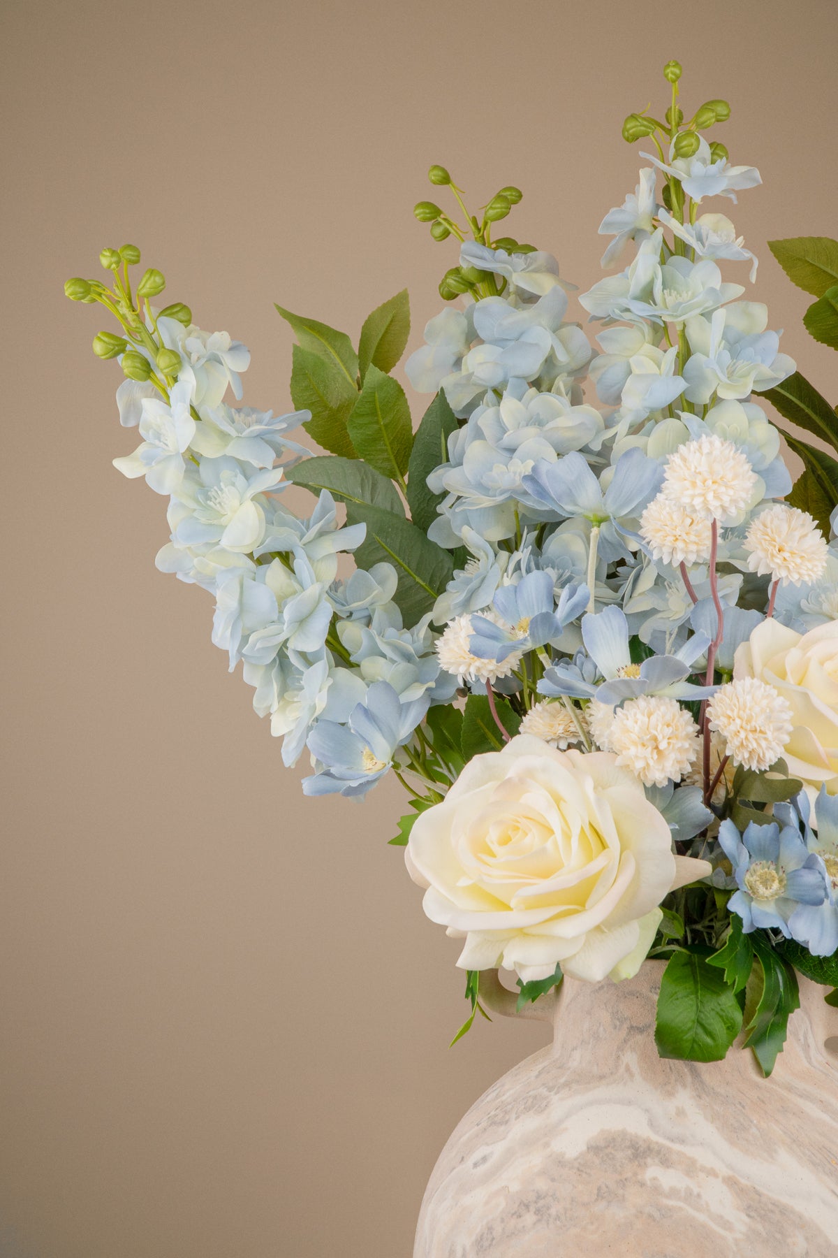 Close-up of blue delphinium spikes and pale blue cosmos in a faux arrangement.