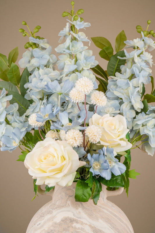 Cream rose and cream pom-pom blooms in a blue and white faux arrangement.