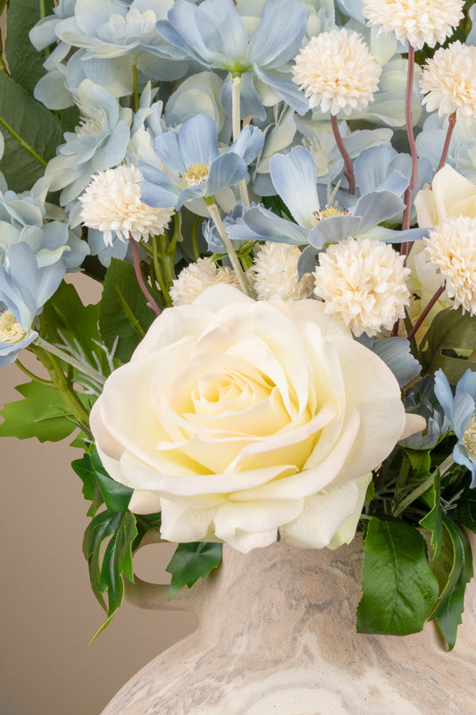 Blue and white faux arrangement styled in a home decor setting.
